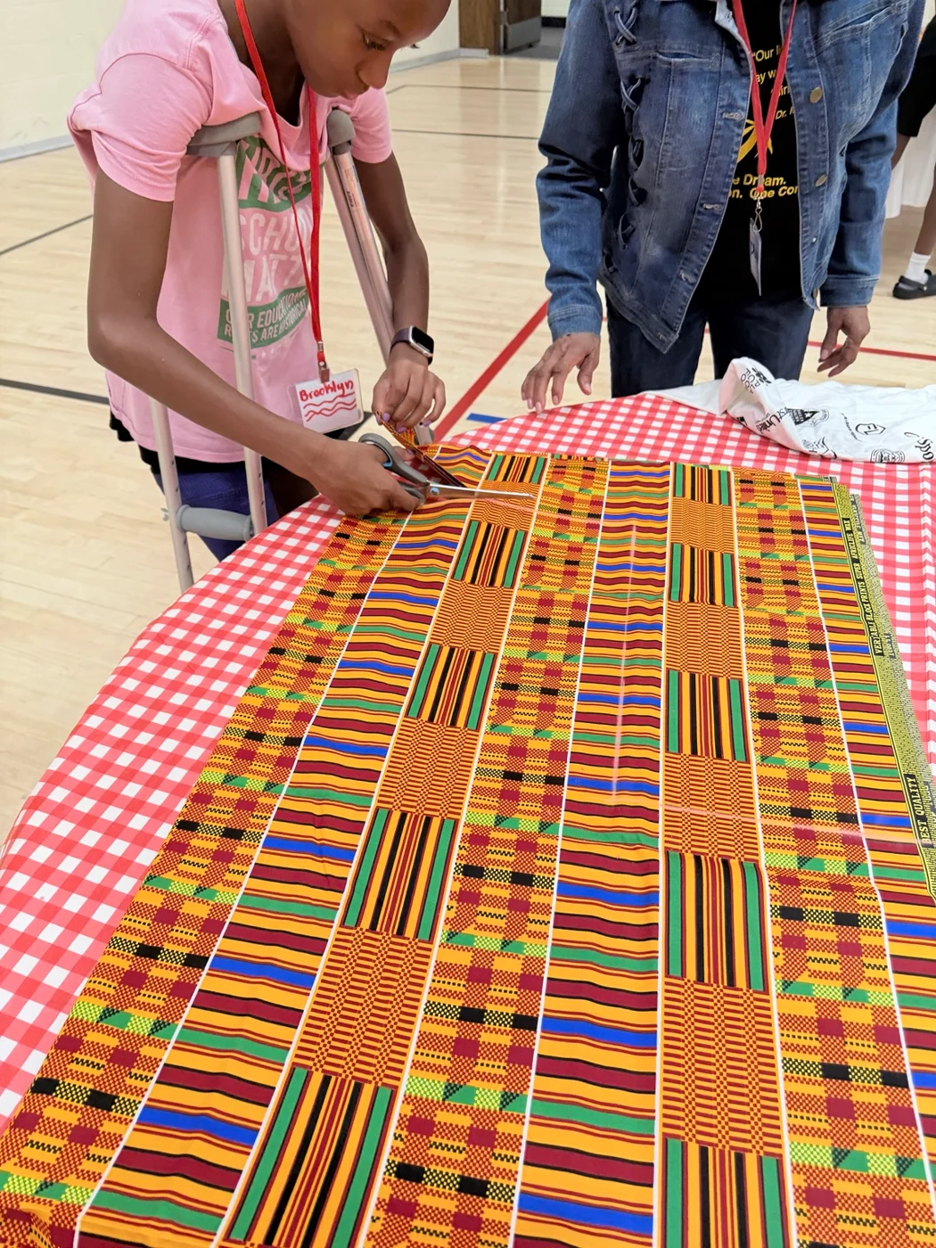 A Freedom School scholar cutting colorful fabric with guidance