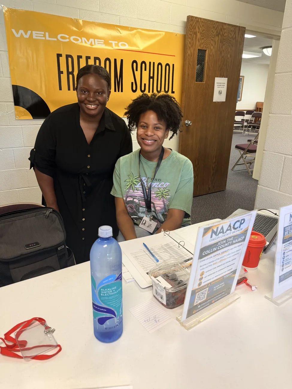 Two people smiling at a Freedom School welcome table