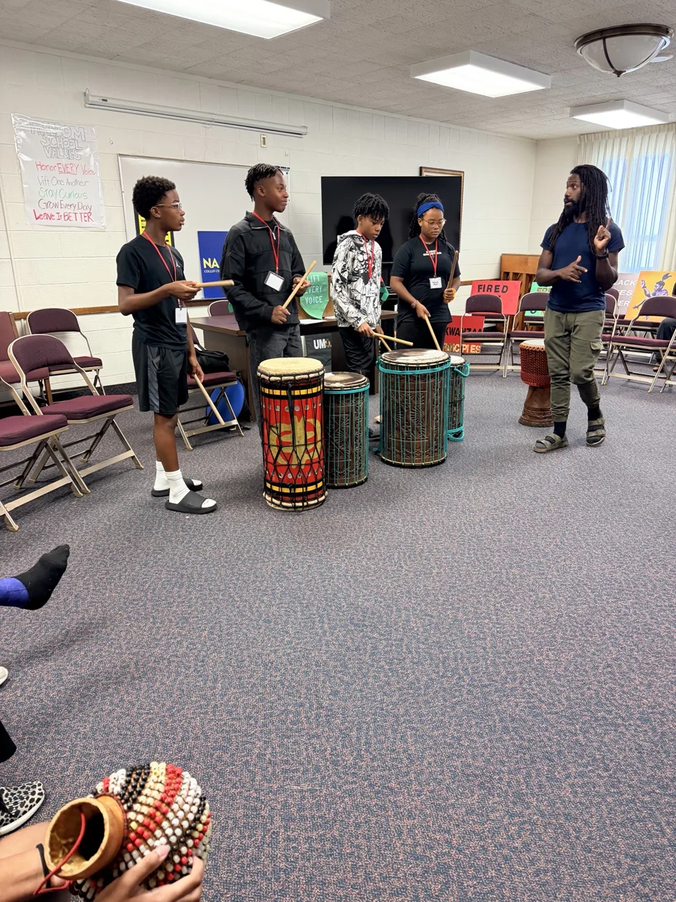 Students and a guest educator participating in an African dance and drumming workshop