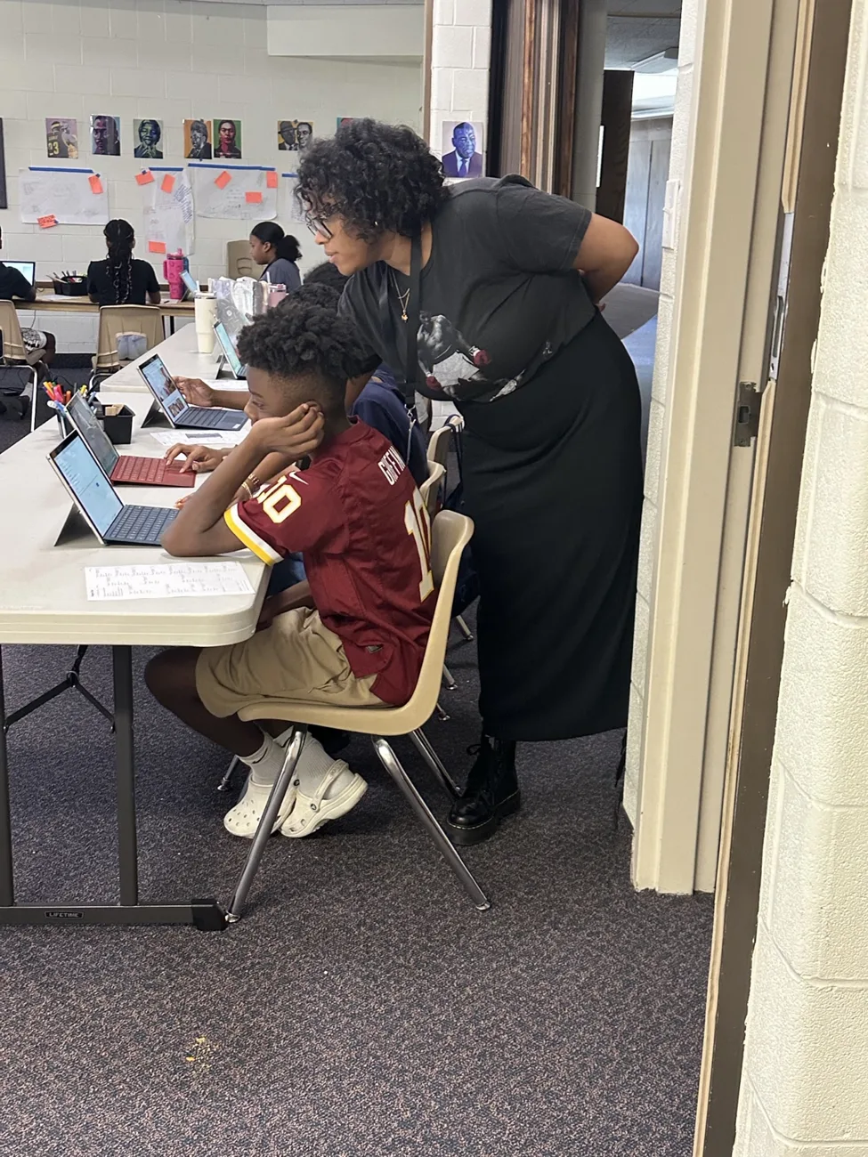 An educator working alongside a seated student